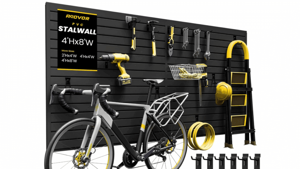 Black horizontal slatwall storage system in a workshop, displaying a bicycle, tools, a cordless drill, hand tools, wrenches, a basket with rope, a yellow hard hat, step ladder, and storage hooks.