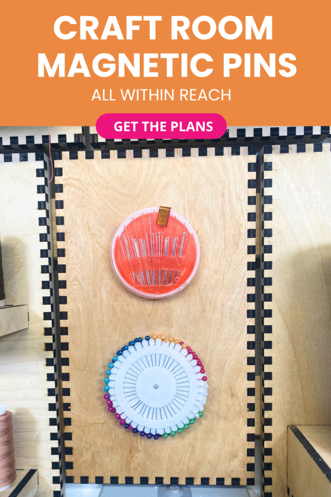 Laser-cut French cleat panel on a plywood wall with two magnetic sewing notions holders, displaying a round case of metal needles and a circular wheel of multicoloured pins above an electrical outlet.
