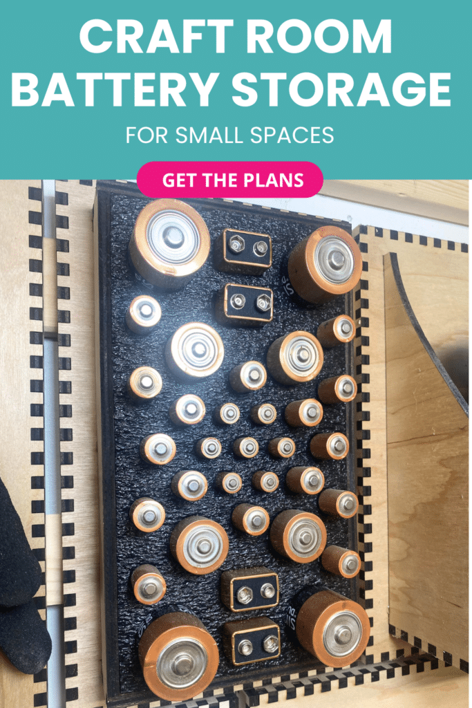 Laser-cut French cleat battery storage panel on a plywood wall, shown from above with a Shadowfoam insert holding assorted AA, AAA, C, D, and 9V batteries in neat rows.