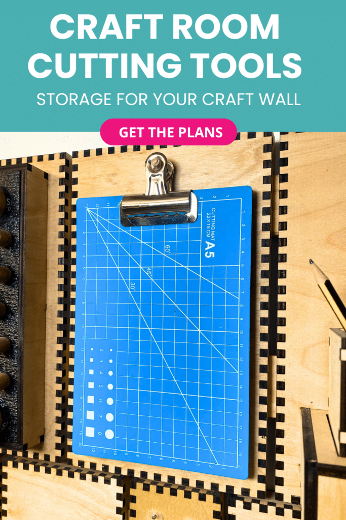 Laser-cut French cleat clipboard holder on a plywood wall, shown at an angle with a bright blue A5 cutting mat clipped to the front for easy access.