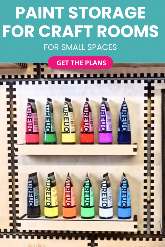 Laser-cut French cleat paint storage rack on a plywood wall, shown front-on with two narrow shelves holding acrylic paint tubes arranged in a rainbow of colours.