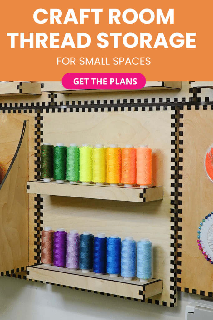 Laser-cut French cleat thread storage panel on a plywood wall, shown at a slight angle with two long shelves holding colorful thread spools arranged in rainbow order.
