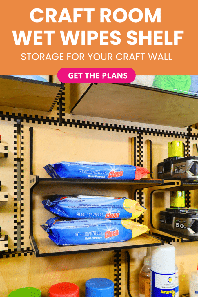 Laser-cut French cleat wet wipes shelf on a plywood wall, shown at an angle with two tiers holding blue packs of cleaning wipes next to cordless tool battery holders.